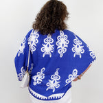 Person wearing a blue patterned top with white background