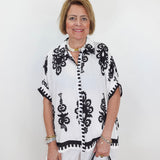 Woman wearing a black and white patterned top with a plain background