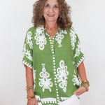 Woman wearing a green and white patterned top against a white background