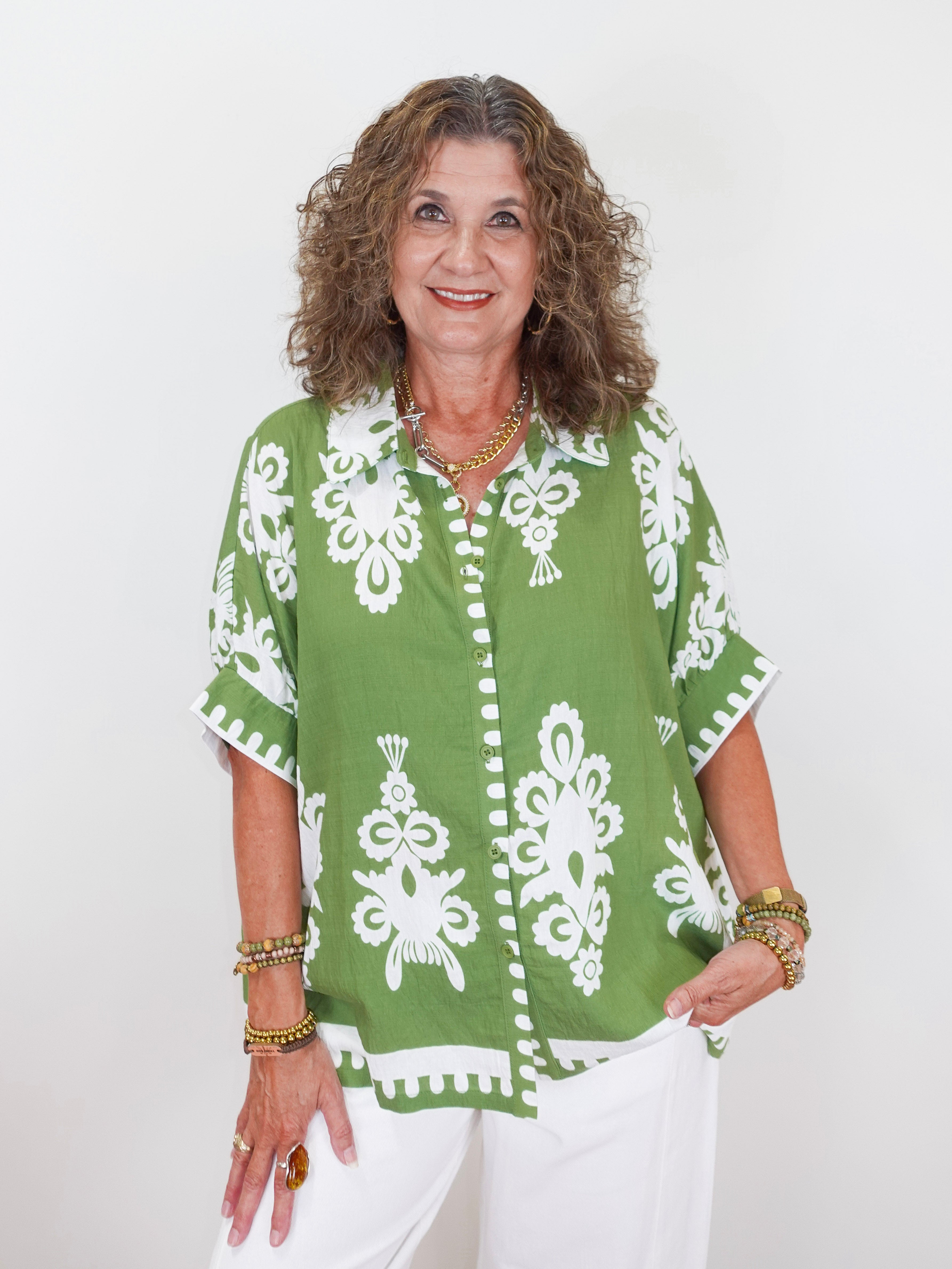 Woman wearing a green and white patterned top against a white background