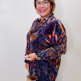Woman wearing a patterned blouse against a plain background
