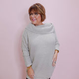 Woman wearing a light gray sweater against a pink wall