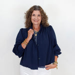 Woman wearing a navy blue jacket and white pants against a white background