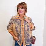 Woman wearing a patterned shirt and jeans against a white background