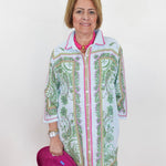 Woman wearing a patterned shirt over a pink top, holding a pink heart-shaped object.