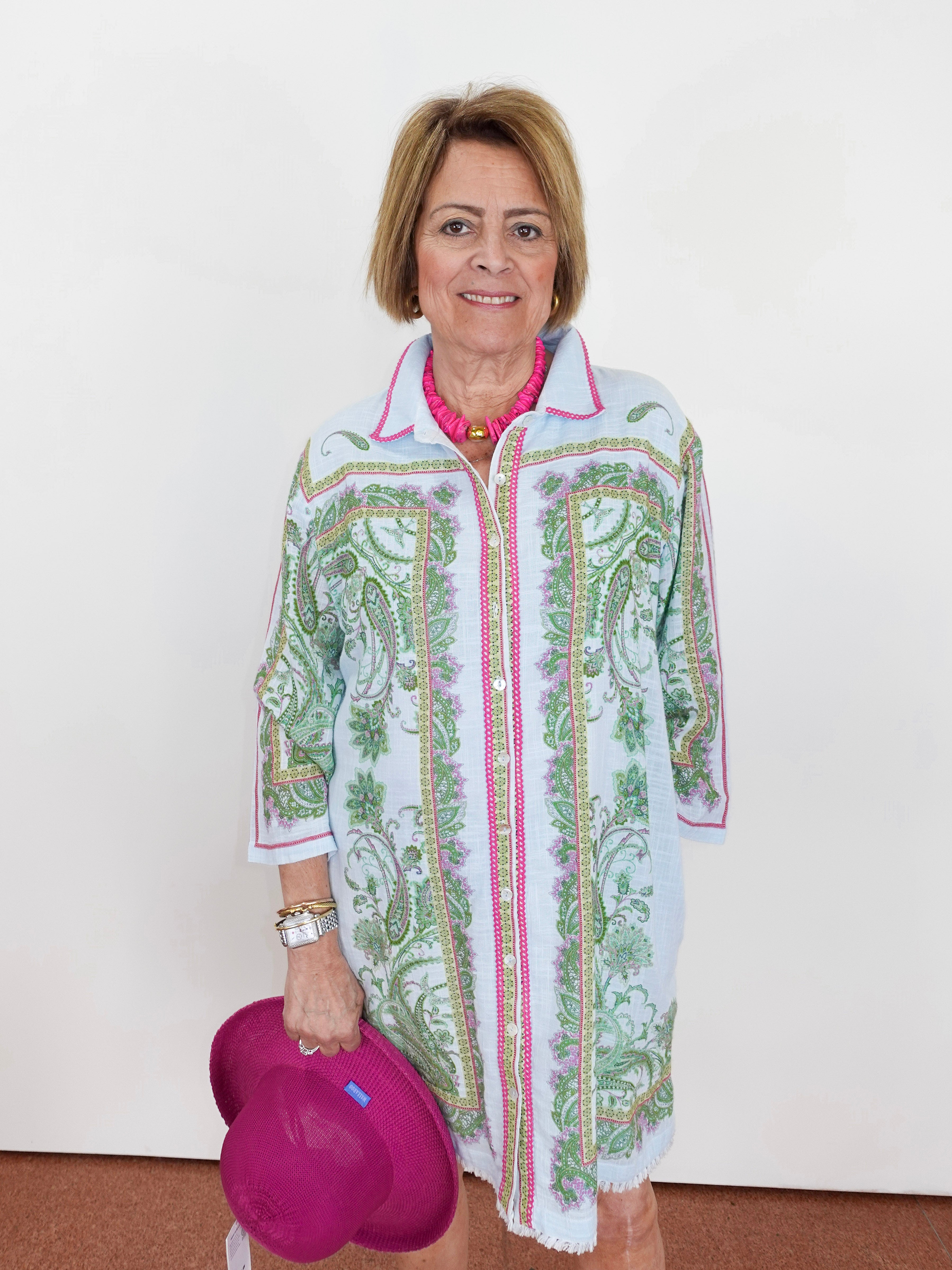 Woman wearing a patterned shirt over a pink top, holding a pink heart-shaped object.