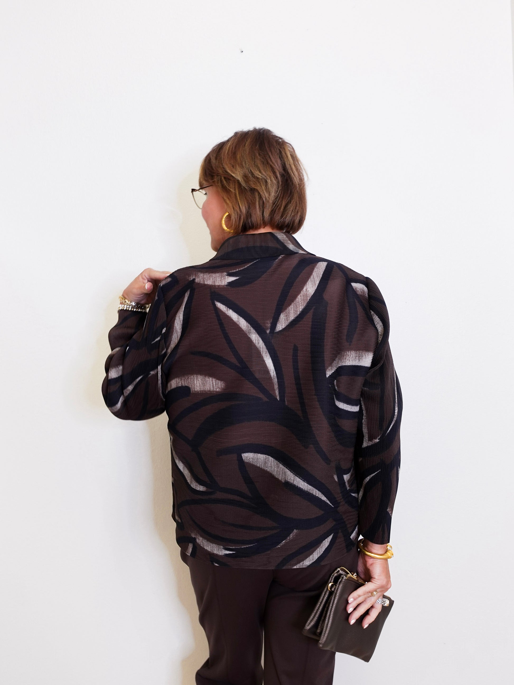 woman wearing a brown blouse against a white background. 