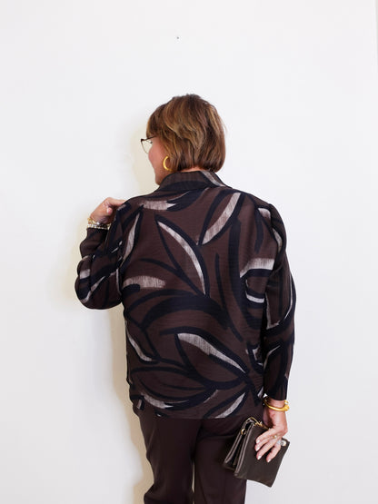 woman wearing a brown blouse against a white background. 