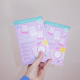 Two packages of 'No Filter' face masks held by a hand against a plain background