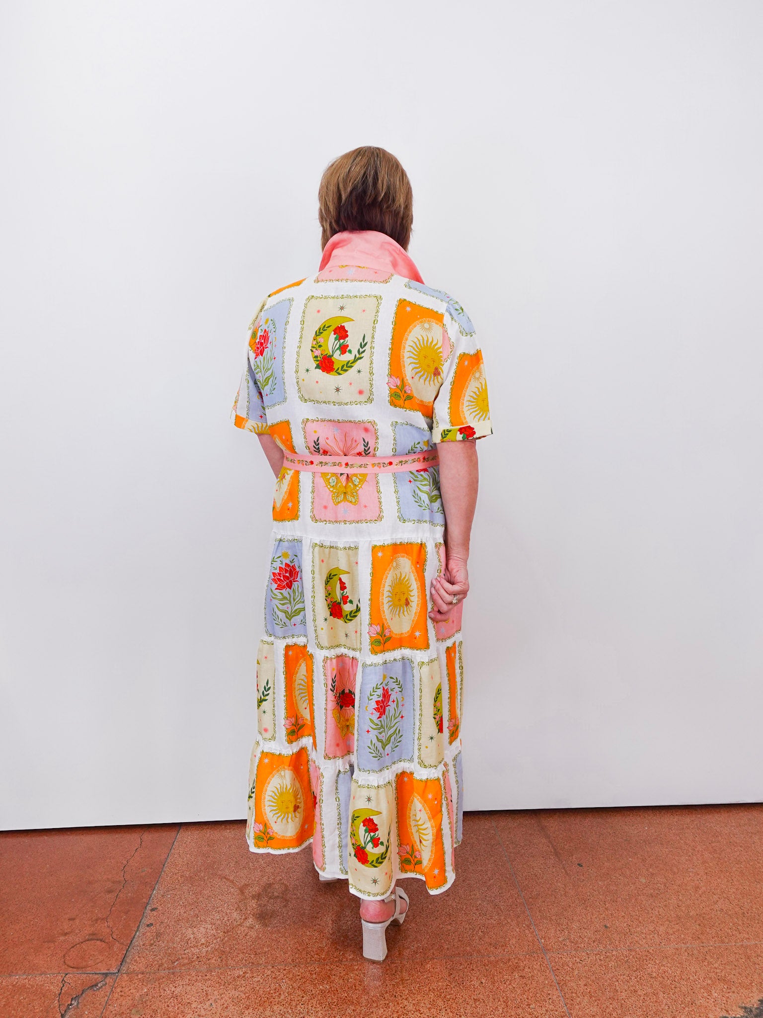 Person wearing a colorful dress with patterned design on a white background