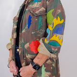 Person wearing a colorful jacket with floral patterns on a plain background