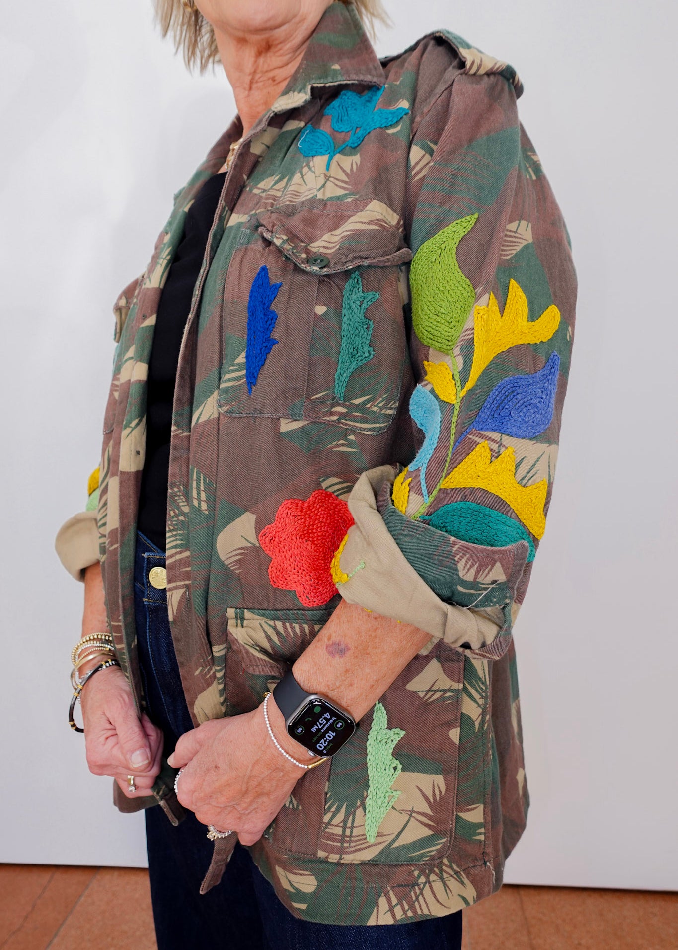 Person wearing a colorful jacket with floral patterns on a plain background