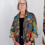 Person wearing a colorful floral-patterned jacket against a white wall.