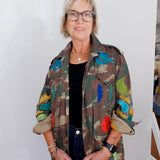 Person wearing a colorful floral-patterned jacket against a white wall.