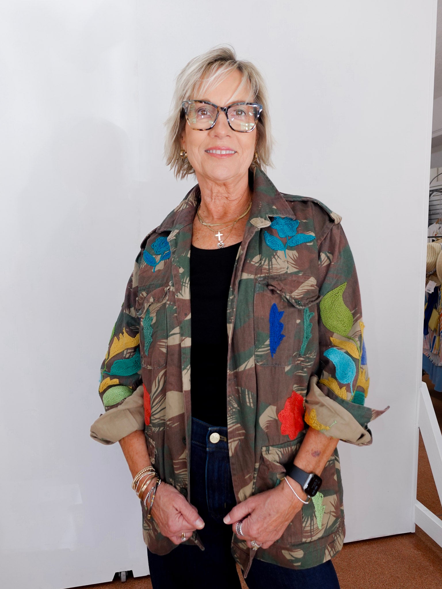 Person wearing a colorful floral-patterned jacket against a white wall.
