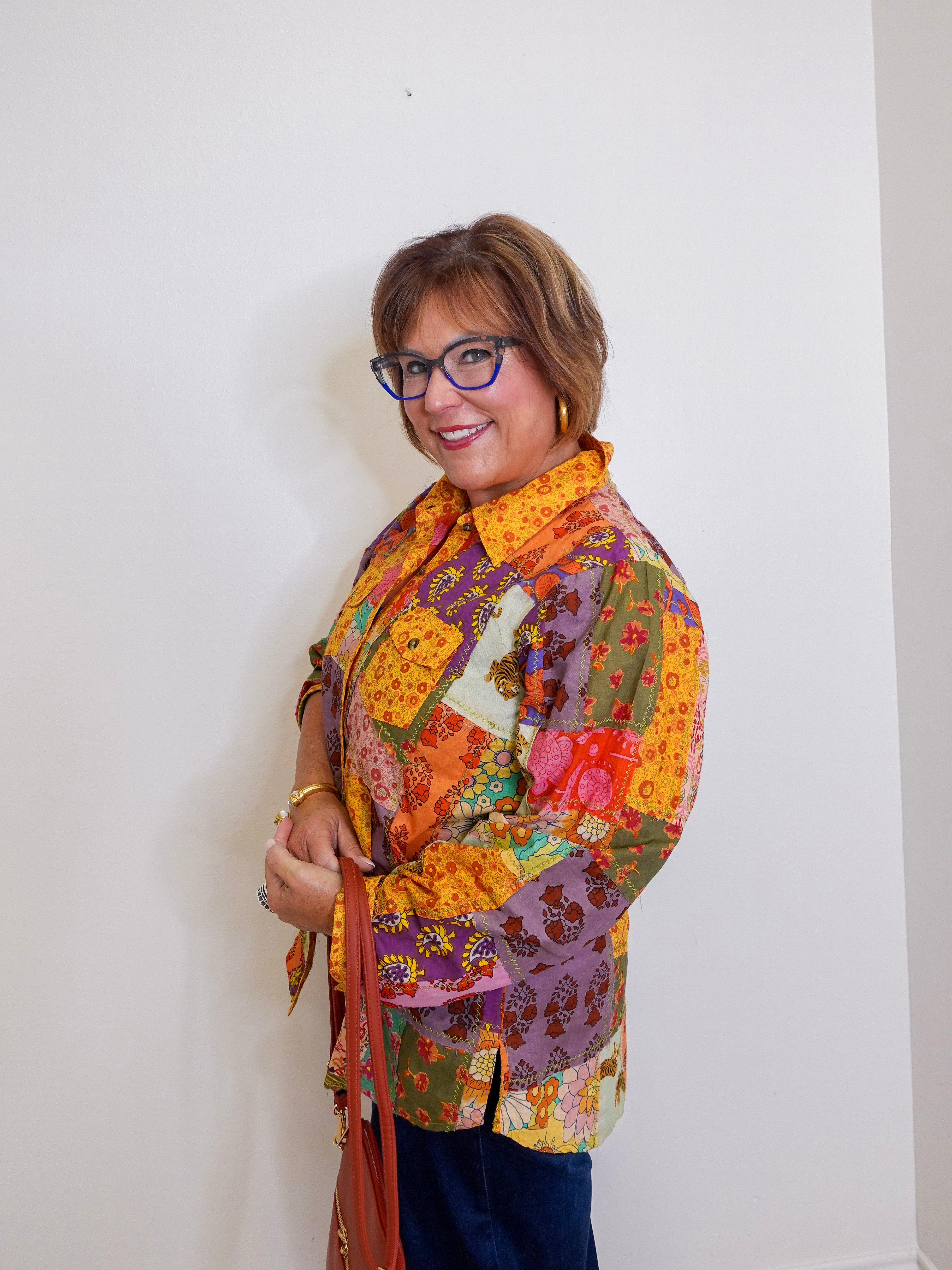 Woman wearing a colorful patchwork jacket against a white background