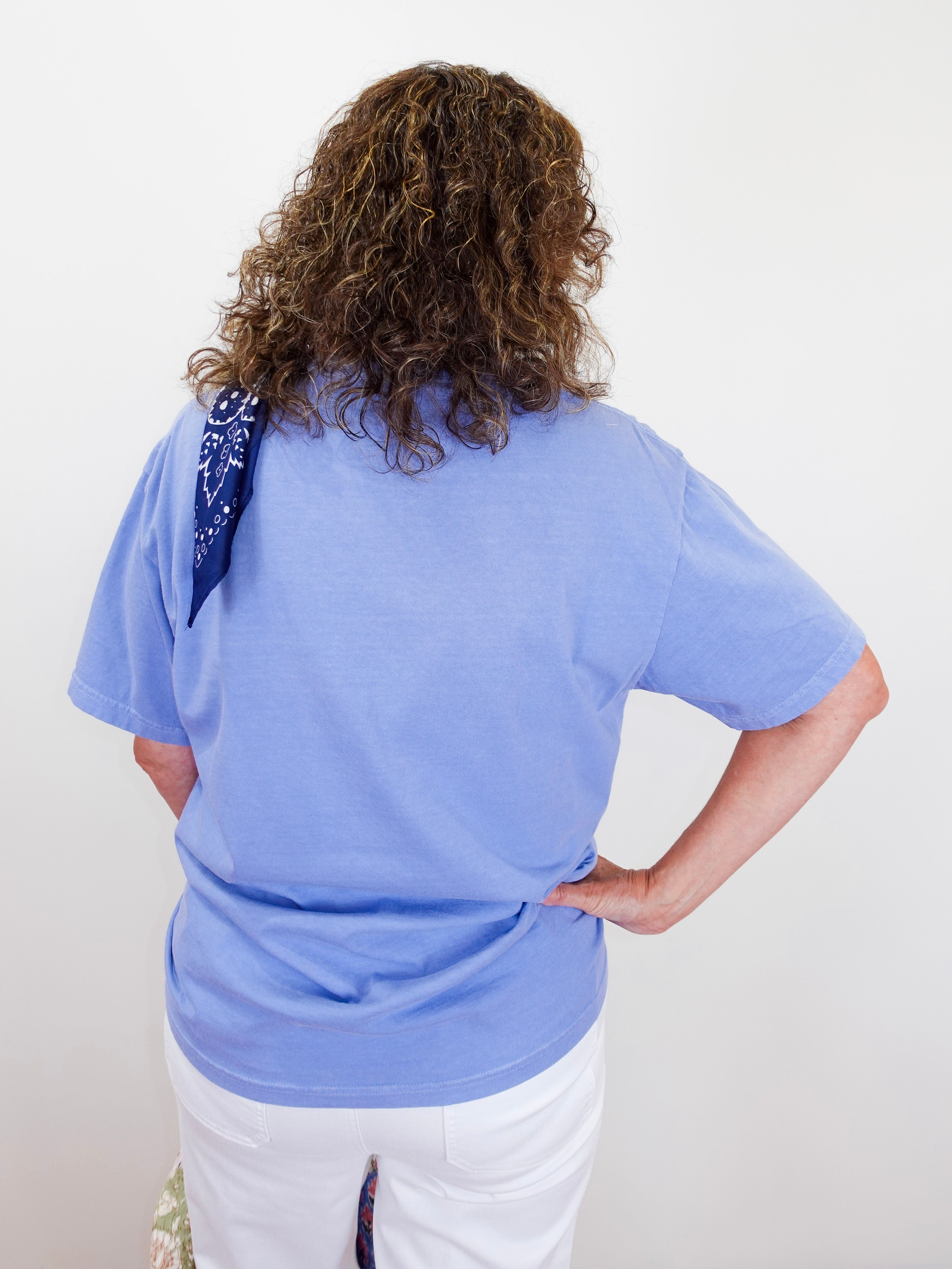 Person wearing a light blue t-shirt with a sequin detail on a plain background