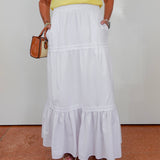 Person wearing a white skirt and yellow top against a plain background