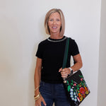 Woman holding a floral handbag against a white wall