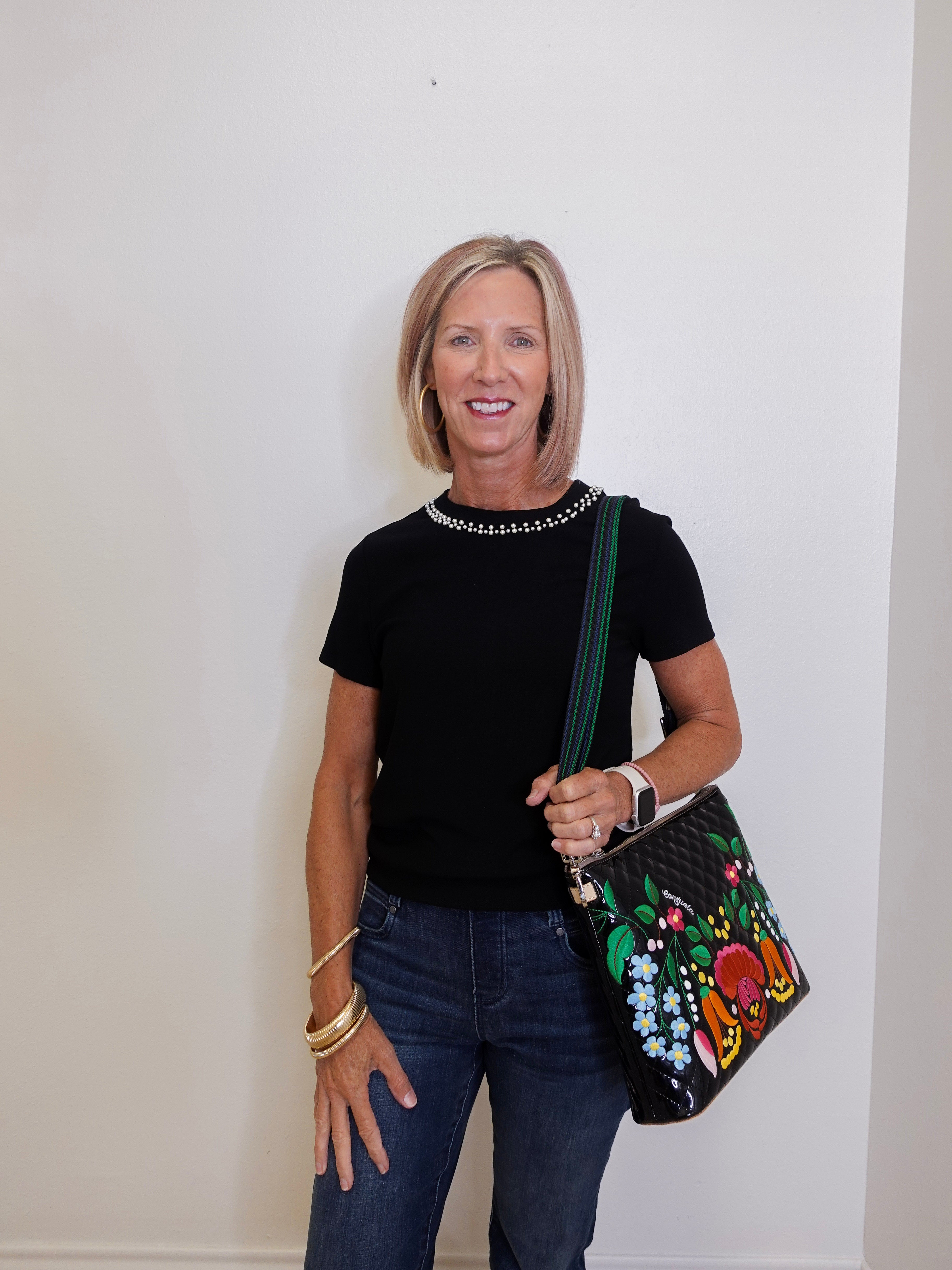 Woman holding a floral handbag against a white wall