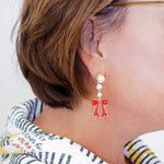 Close-up of an earring with a red bow design on a white background