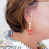 Close-up of an earring with a red bow design on a white background