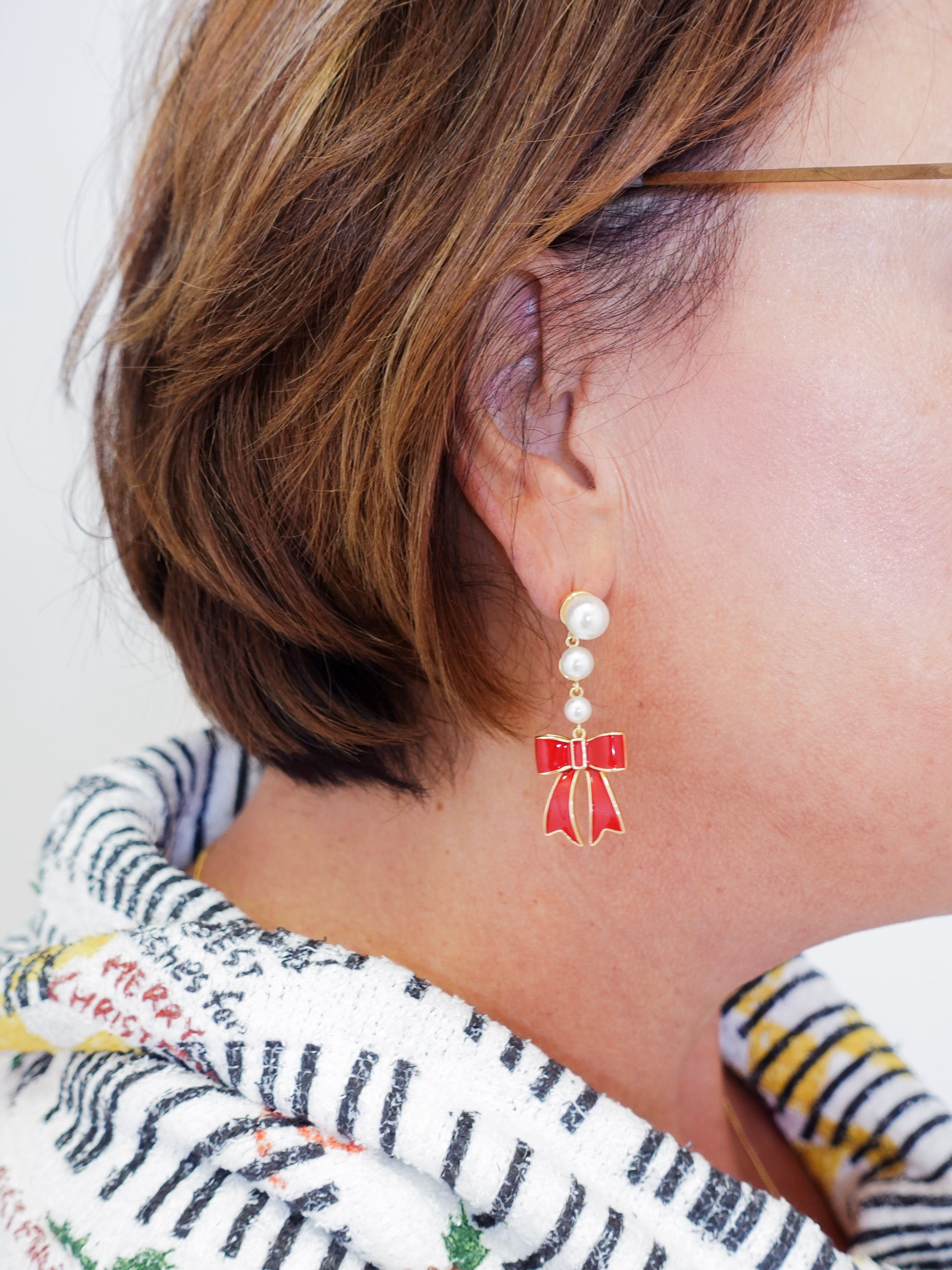 Close-up of an earring with a red bow design on a white background