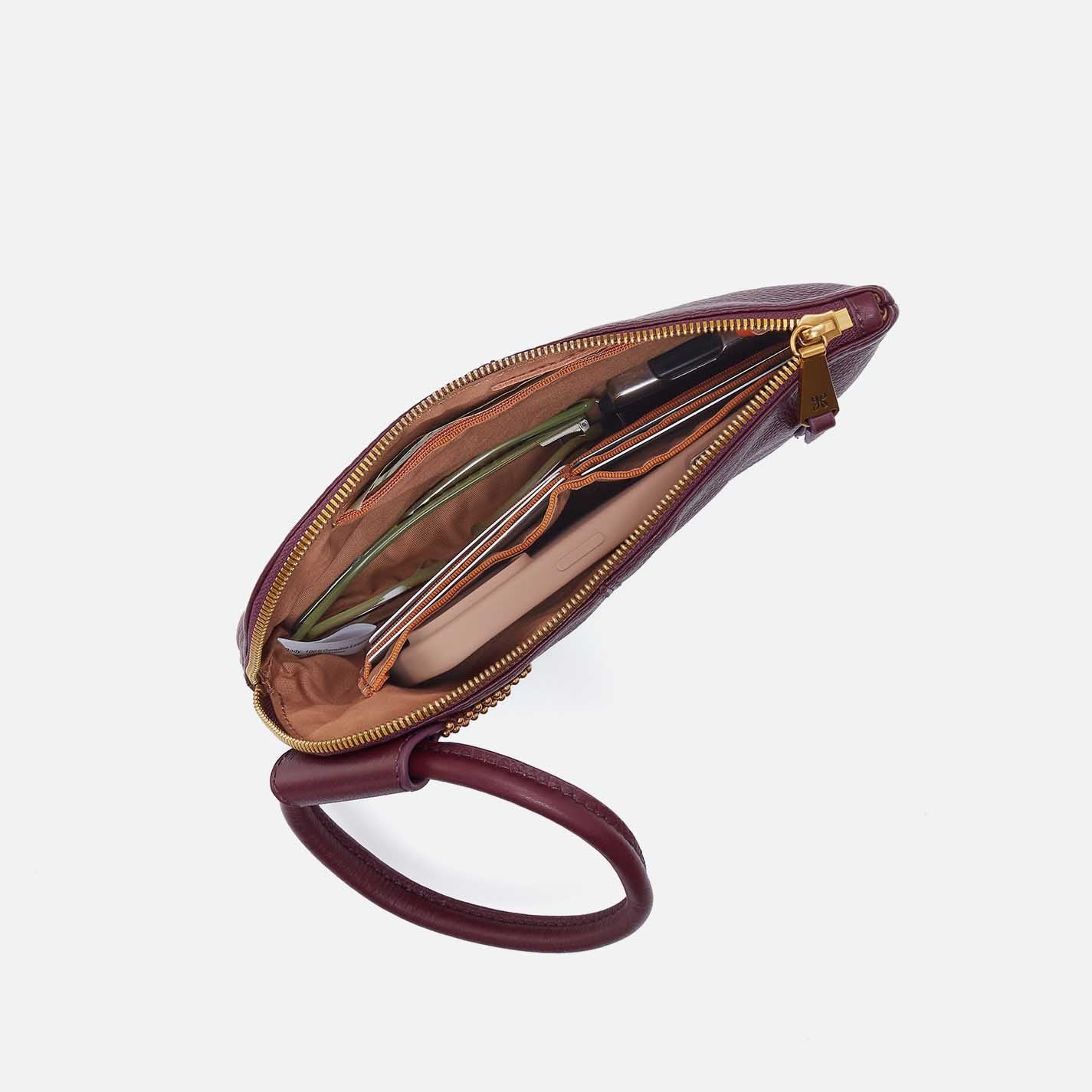 Brown leather wristlet with open zipper on a white background