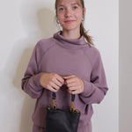 woman wearing the Black handbag with gold accents on a white background.