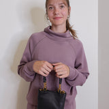 woman wearing the Black handbag with gold accents on a white background.