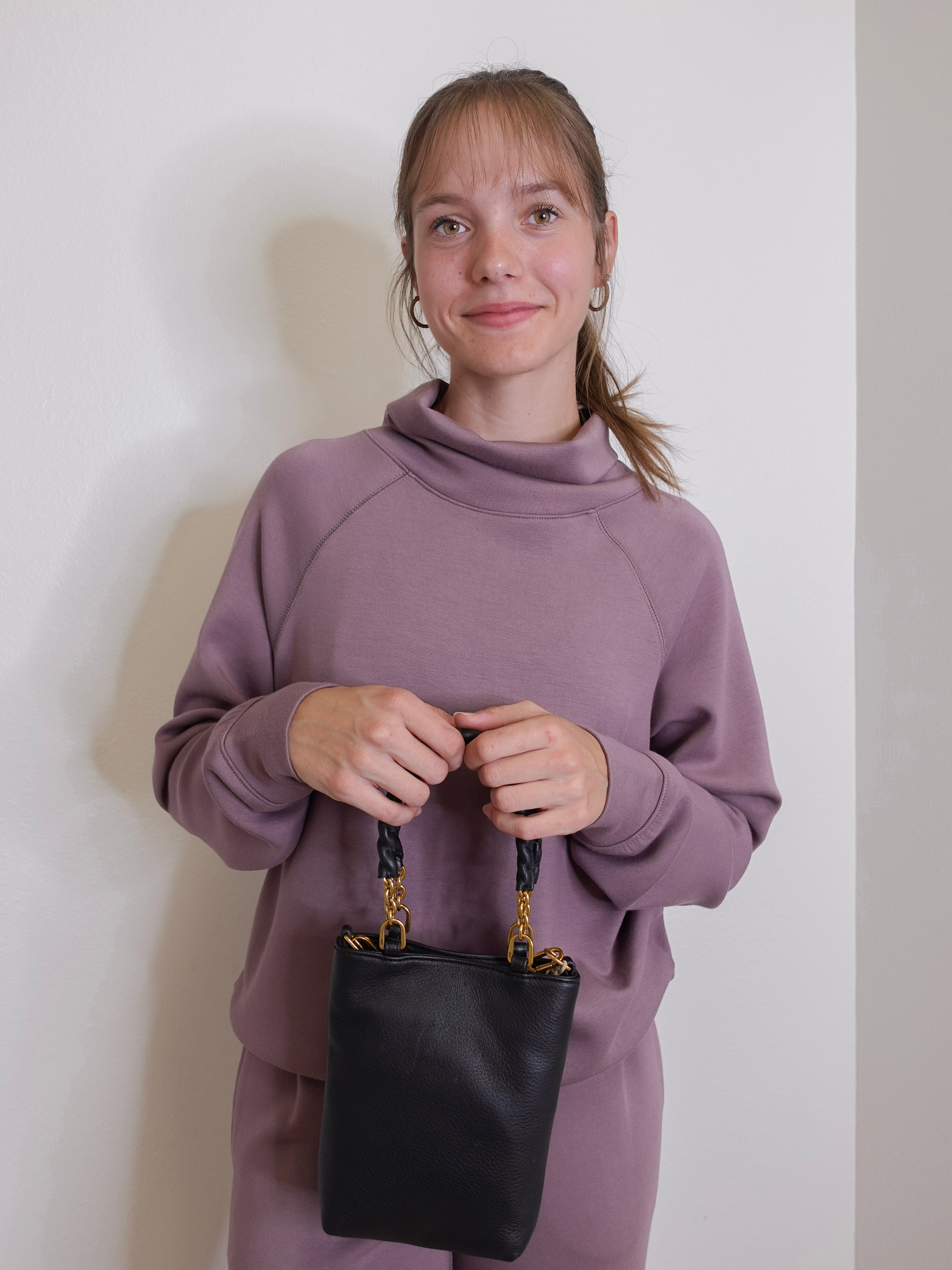 woman wearing the Black handbag with gold accents on a white background.
