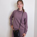 woman wearing the Black handbag with gold accents on a white background.