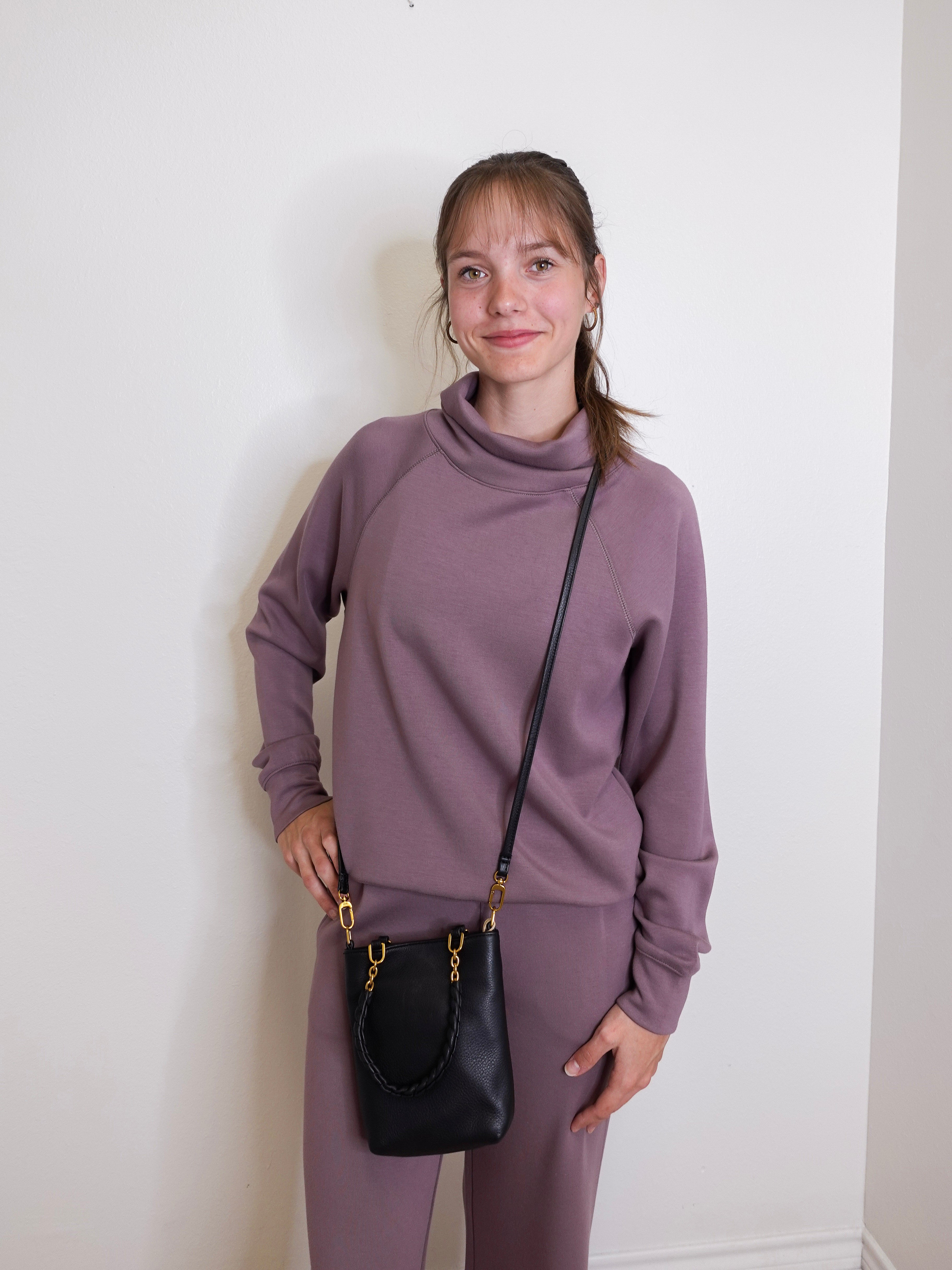 woman wearing the Black handbag with gold accents on a white background.