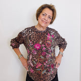 Woman wearing a leopard print blouse with floral embroidery against a white background