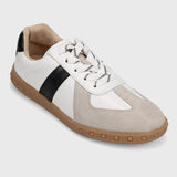 White and beige sneaker with a black stripe on a light gray background