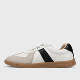 White sneaker with black accent and brown sole on a light gray background