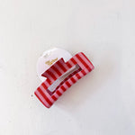 Red and white striped hair clip on a light gray background