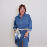 Woman wearing a blue denim dress with a white wall background