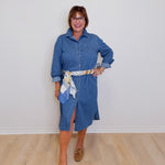 Woman wearing a blue denim dress with a white wall background
