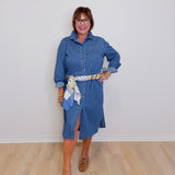 Woman wearing a blue denim dress with a white wall background