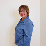 Woman wearing a blue denim jacket against a plain background