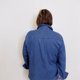 Person wearing a blue denim shirt against a white background