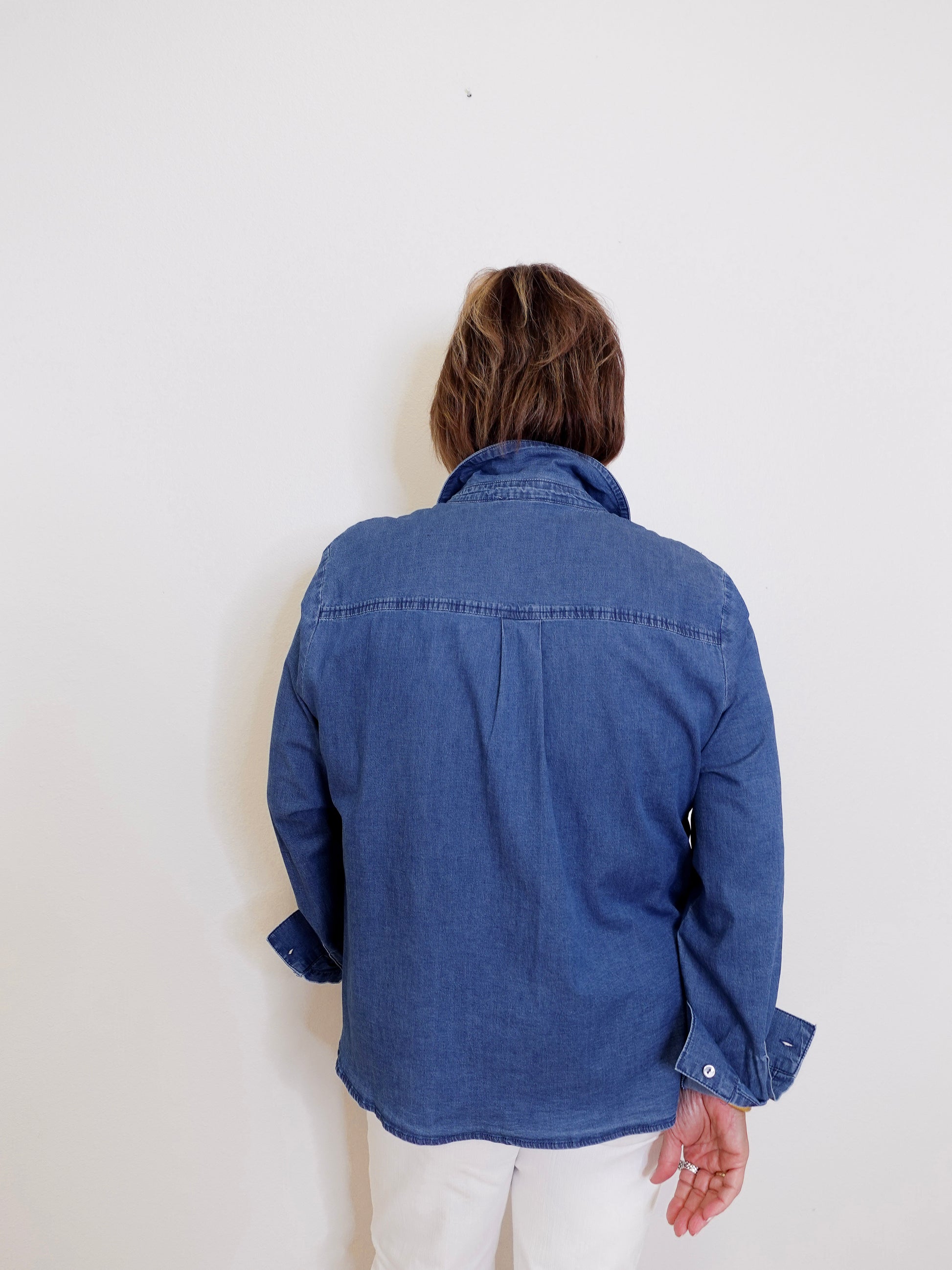 Person wearing a blue denim shirt against a white background
