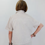 Person wearing a beige striped shirt and pants against a white background