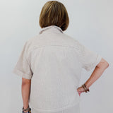 Person wearing a beige striped shirt and pants against a white background