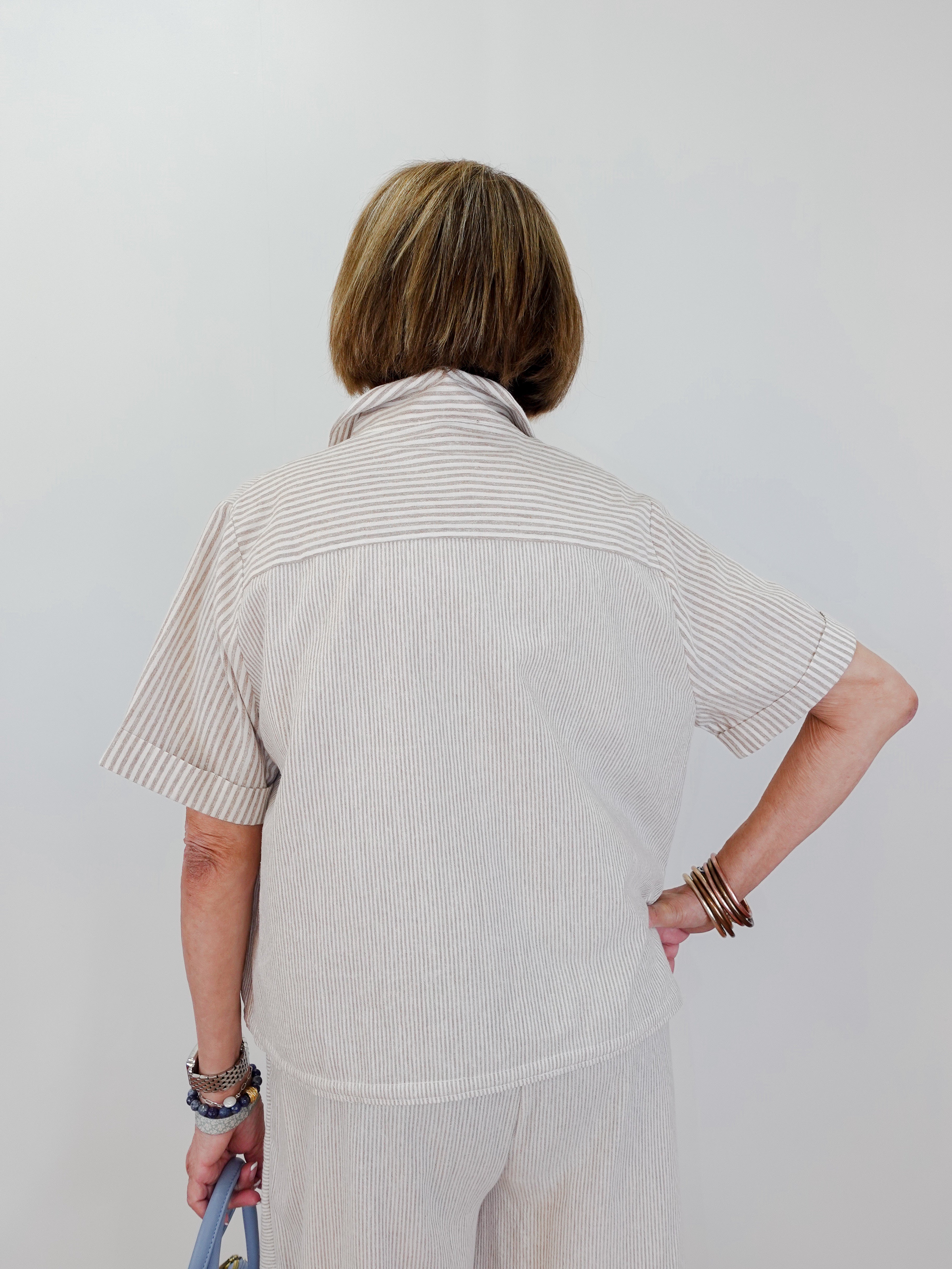Person wearing a beige striped shirt and pants against a white background