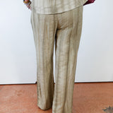 Person wearing a beige suit with a white wall background