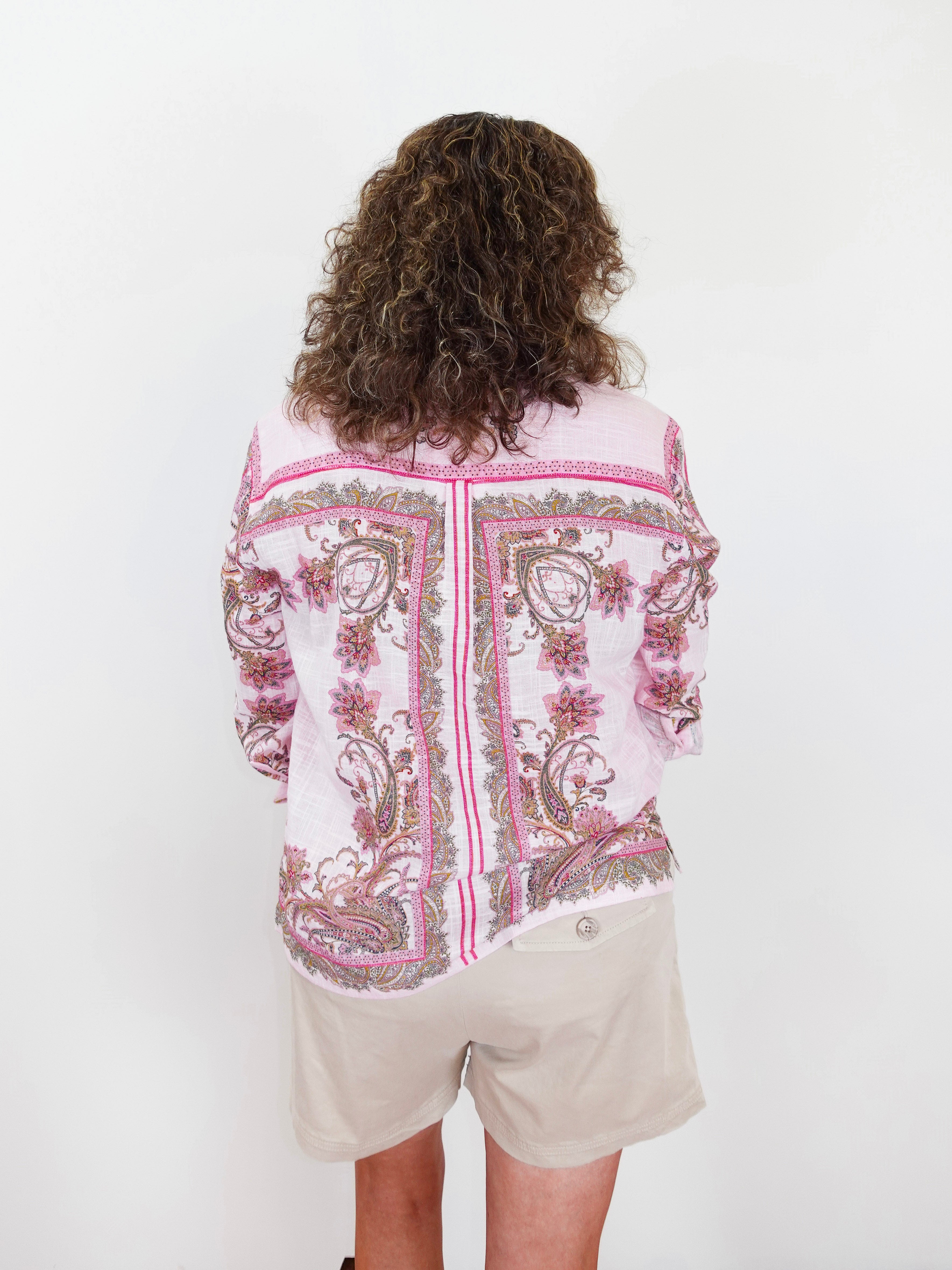 Person wearing a patterned shirt and shorts on a white background