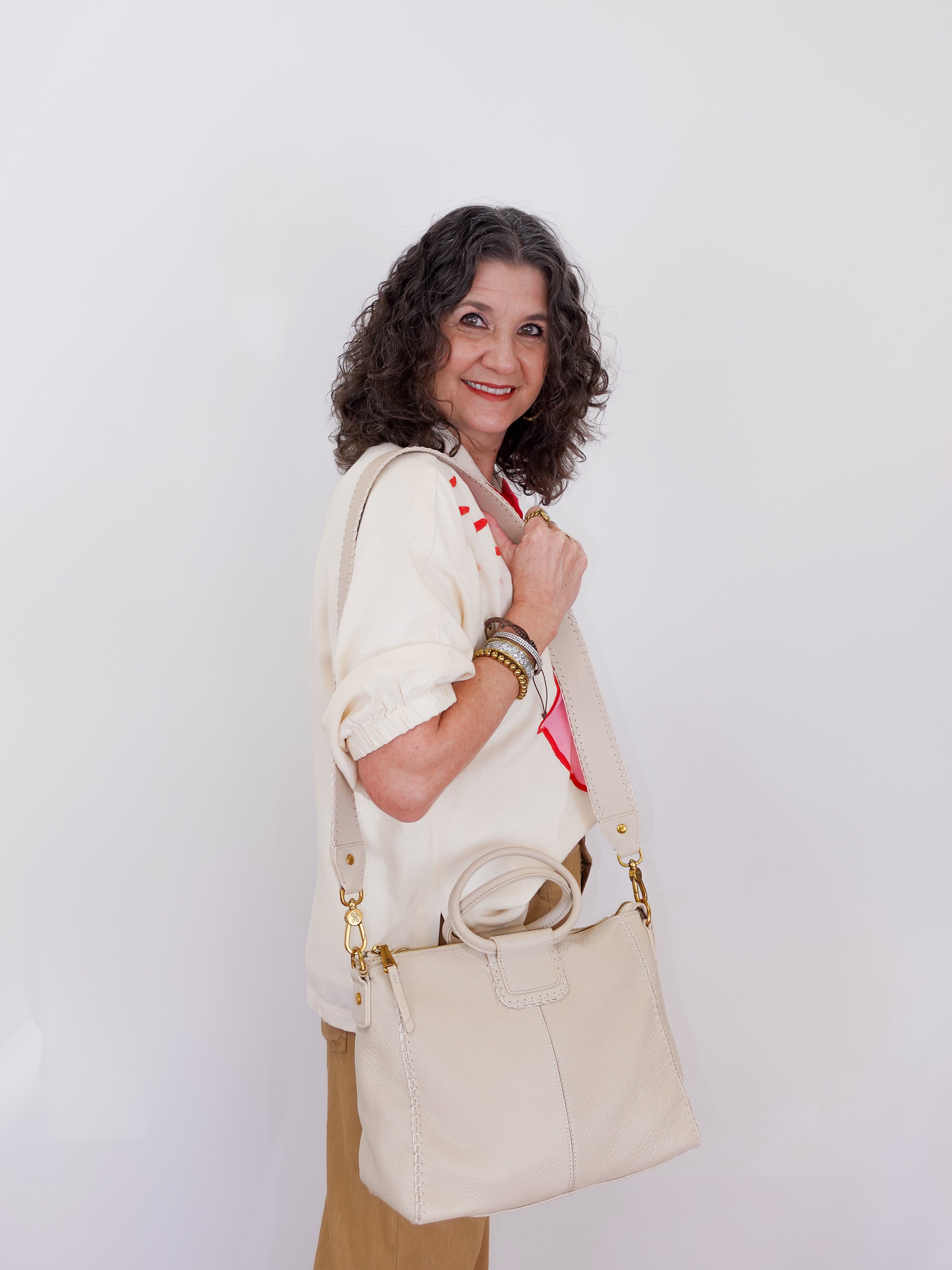 Woman holding a beige handbag against a white background