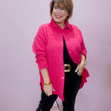 Woman wearing a pink quilted jacket and black pants against a plain background